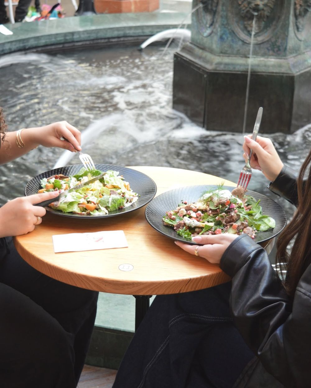 Two salads at a table by the fountain at Nadia's Café